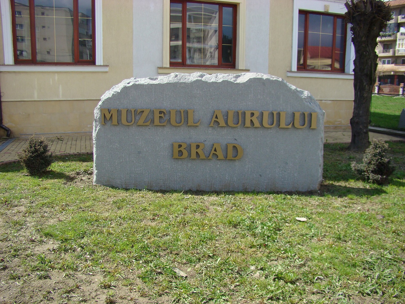 Piatra cu inscripția „Muzeul Aurului Brad” din fața muzeului